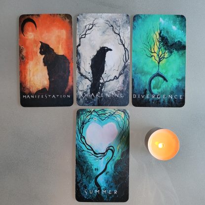 Four oracle cards laid out on a glass table with a lit candle.